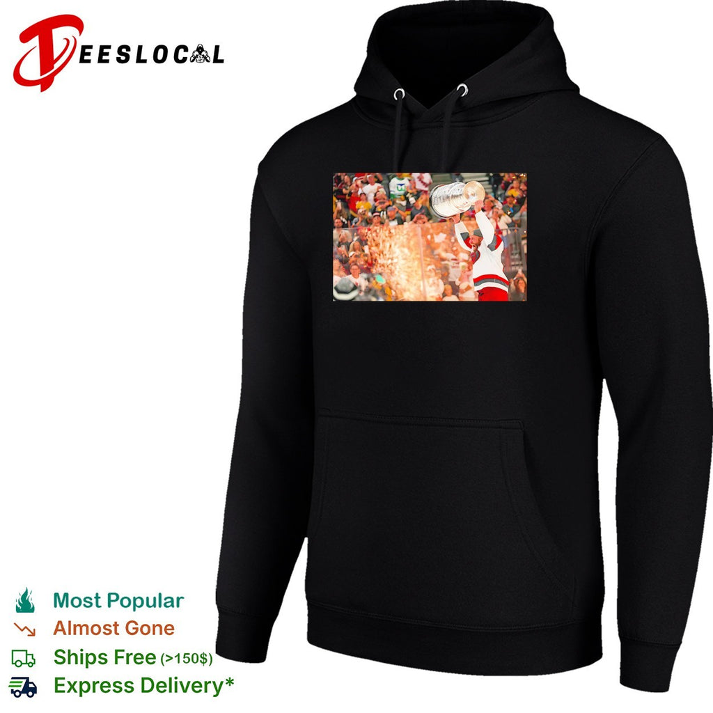 Carolina Hurricanes player hoisting Stanley Cup above head crowd fireworks triumphant moment shirt